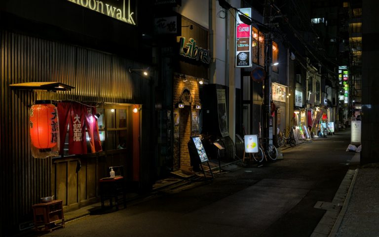 A city street at night with people walking on the sidewalk