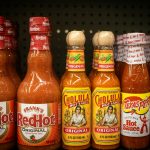 Hot sauce bottles line a store shelf.
