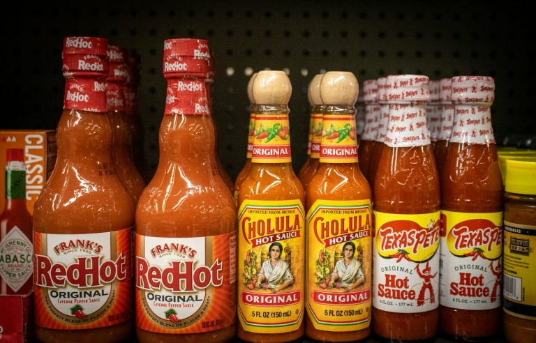 Hot sauce bottles line a store shelf.